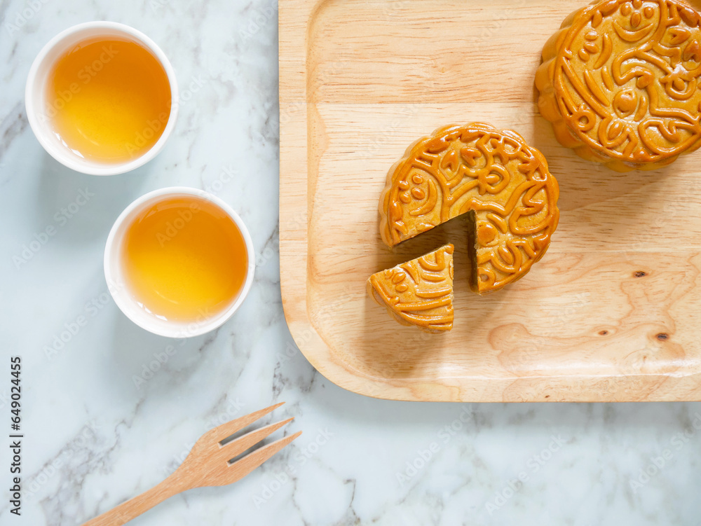 Mooncakes on a wooden plate with cups of tea for Mid-Autumn Festival or Harvest Festival Mooncakes on a wooden plate with cups of tea for Mid-Autumn Festival or Harvest Festival