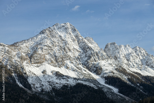 View of snow peaked mountains from Valle di Cadore town. Blue sky in a sunny winter day; Dolomites, Italian alps, Italy