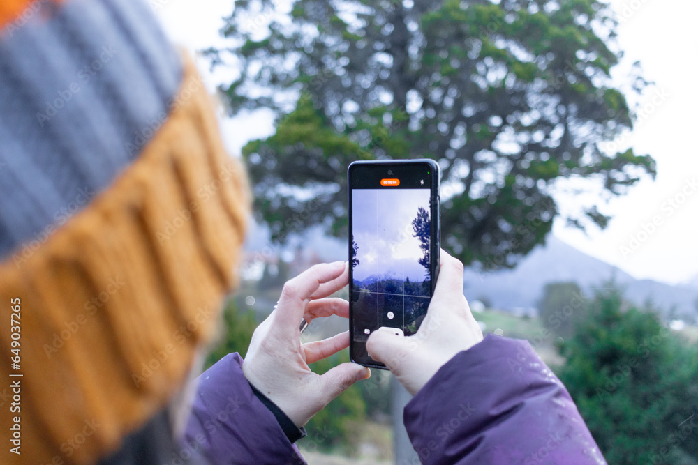 Woman recording video through her smartphone in wooded and cloudy landscape. Woman recording video through her smartphone in wooded and cloudy landscape.
