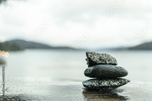 Tower of zen stones on wet wood with lake background.