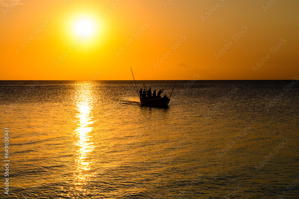 Silhouettes of the fishermen in boat against sunset. Zanzibar, Tanzania