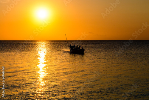 Silhouettes of the fishermen in boat against sunset. Zanzibar, Tanzania