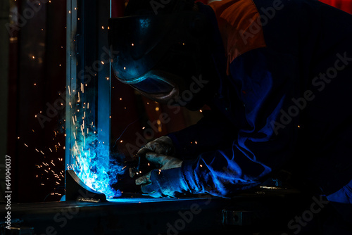 Skillful metal worker working with arc welding machine in factory while wearing safety equipment. Metalwork manufacturing and construction maintenance service by manual skill labor concept