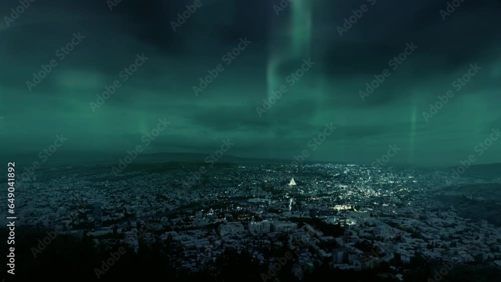 Bright aurora borealis shining in night sky over mountain city is