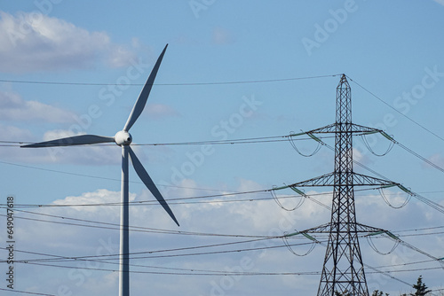 Wind turbine and electricity pylon on blue sky background