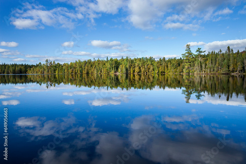 Beautiful blue lake in northern Minnesota with pines along the shore and clouds reflecting in calm water photo