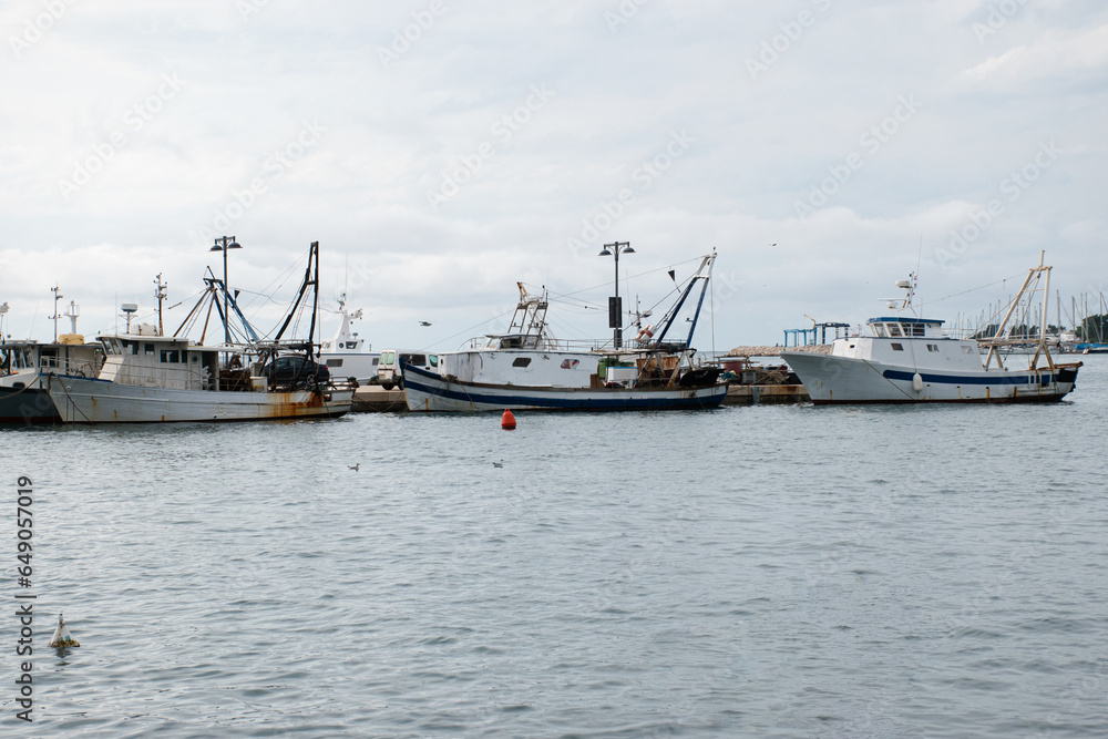 Three big fishing boats being anchored by the stone dock in Umag, Croatia.