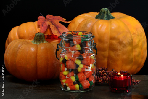 Pumpkins, Halloween candy and a lit candle.