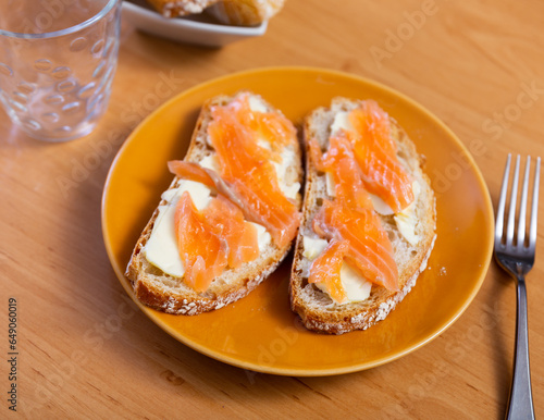 Two delicious sandwiches with salmon and butter on a plate. Close-up image