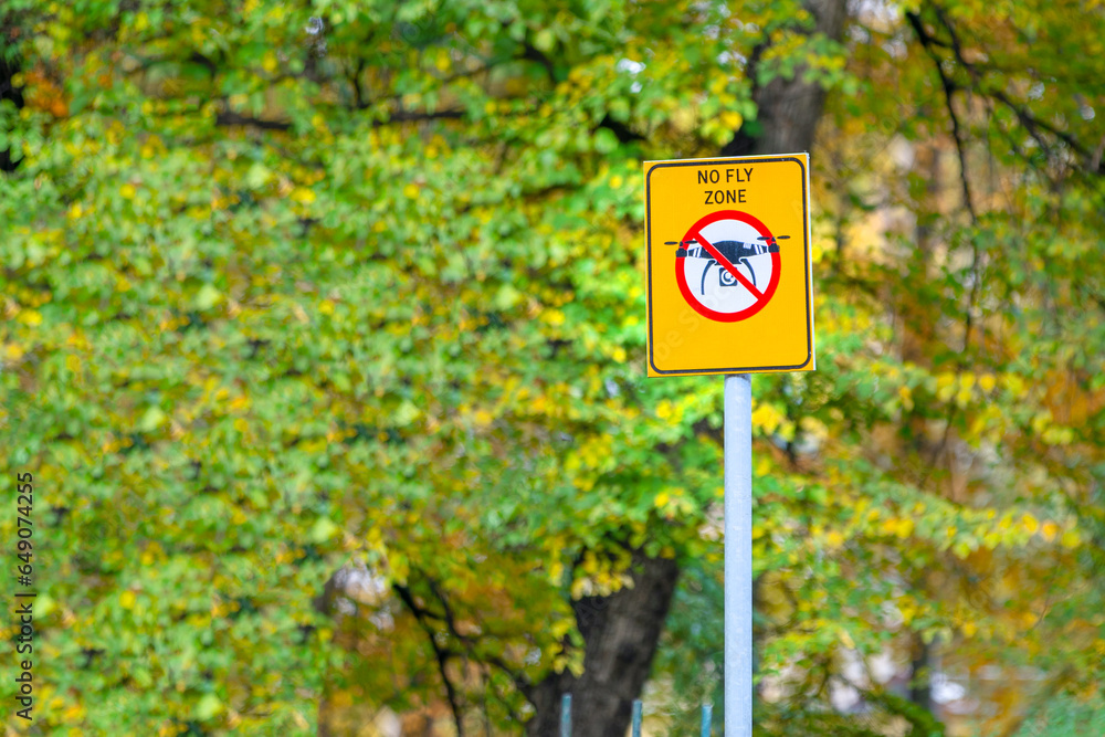 Prohibiting yellow square sign no fly zone drone against background of trees, public park. Safety of tourists, secret object, protected area Aircraft restriction in national parks, untouched nature Prohibiting yellow square sign no fly zone drone against background of trees, public park. Safety of tourists, secret object, protected area Aircraft restriction in national parks, untouched nature