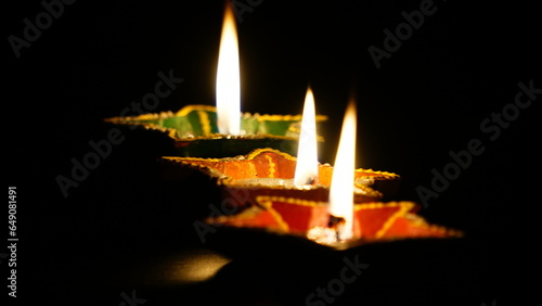 Happy Diwali, Lit Diya lamp on a black background.