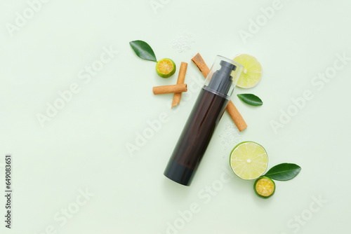 Few cinnamon sticks  slices of lime and kumquat arranged on light background with unbranded bottle. Copy space. Lime and Kumquat are rich in vitamin C and antioxidants