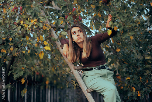 Obraz na plátně Woman Climbing a Wooden Ladder to Harvest apples