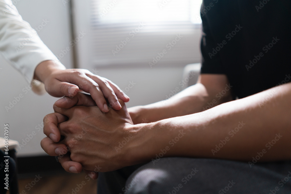 Psychologist woman touching hands to encouraging man with mental health problem in therapy center