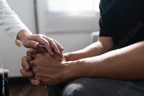 Psychologist woman touching hands to encouraging man with mental health problem in therapy center
