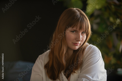 Fotografie Young poet with long brown hair muses in her study by the light of a nearby window