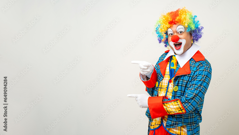 Mr Clown. Portrait of Funny comedian face Clown man in colorful uniform pointing finger to copy space for text advertise. Happy expression amazed male bozo in various pose on isolated background.