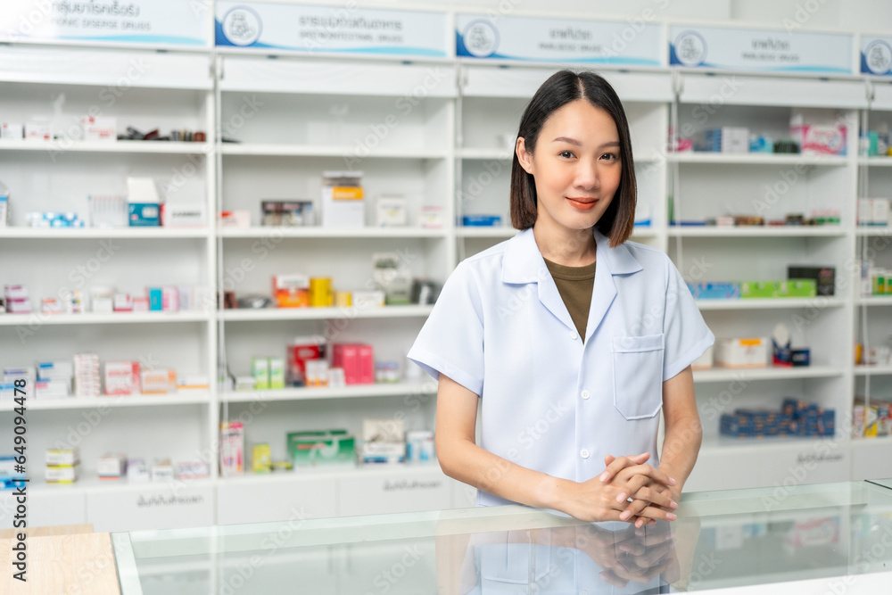 Beautiful asian woman pharmacist checks inventory of medicine in pharmacy drugstore. Professional Female Pharmacist wearing uniform standing near drugs shelves counter