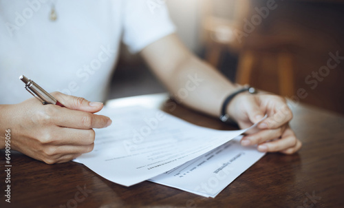 Young asian woman sitting at desk reading application documents to find a job after graduating, reviewing application before filling out job application details, close-up view
