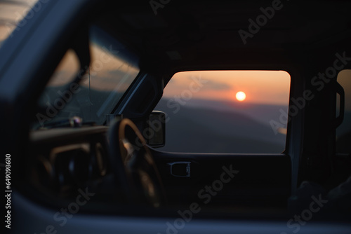 View of sunset in mountains through glass of off-road car.