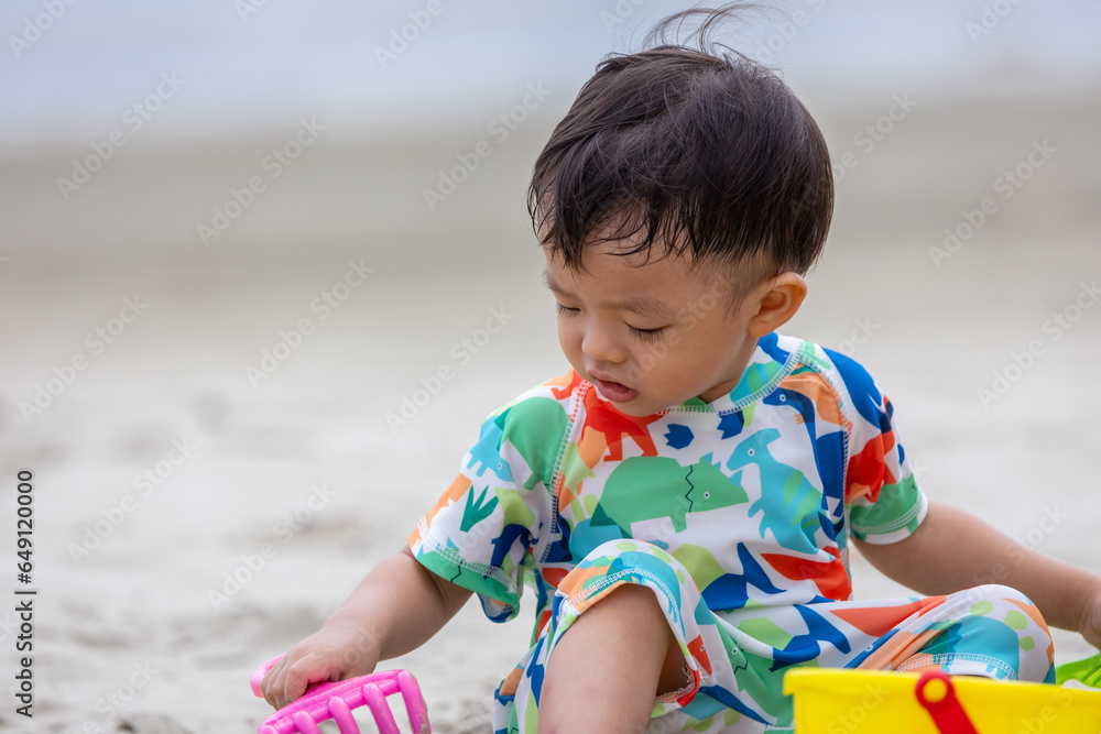 Happy 1-2 years old child enjoying playing on beach with splashing warm sea water Happy 1-2 years old child enjoying playing on beach with splashing warm sea water
