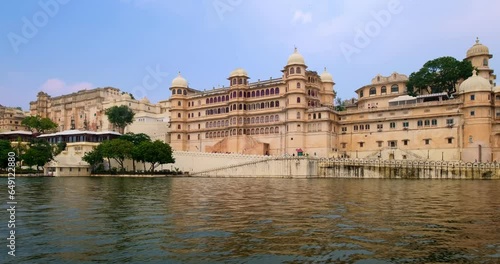 Udaipur City Palace view from moving boat on lake Pichola. Luxury white palace is Rajput architecture of Mewar dynasty rulers of Rajasthan and famous tourist Indian landmark. Incredible India heritage