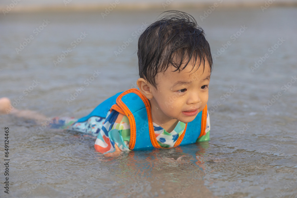 Happy Asian Chinese child playing in the beach. Kid having fun outdoors. Summer vacation and healthy lifestyle concept Happy Asian Chinese child playing in the beach. Kid having fun outdoors. Summer vacation and healthy lifestyle concept