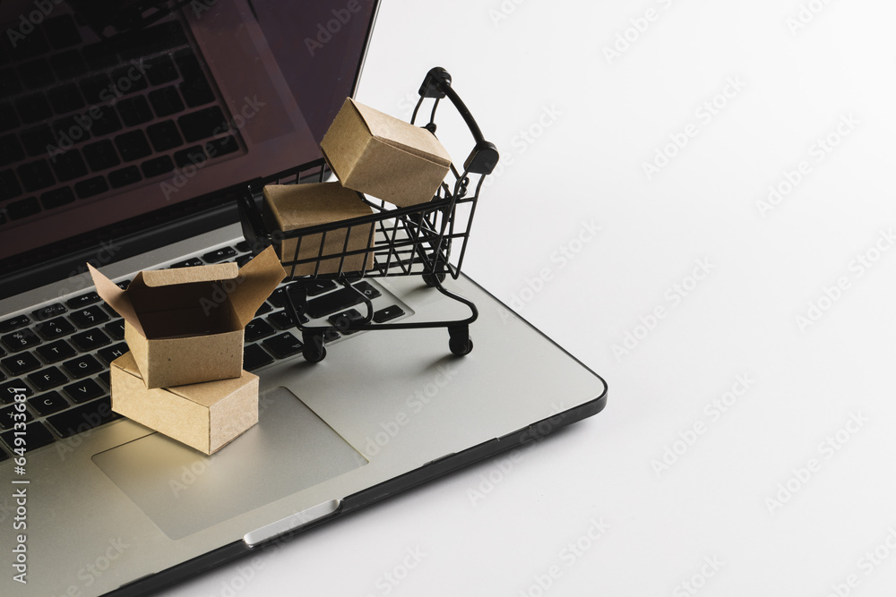 Laptop with blank screen, shopping trolley and gift boxes with copy space on white background Laptop with blank screen, shopping trolley and gift boxes with copy space on white background