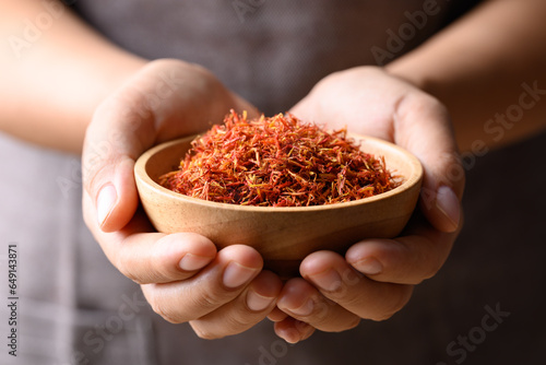Canvas-taulu Dried safflower in wooden bowl holding by hand, Herbal tea