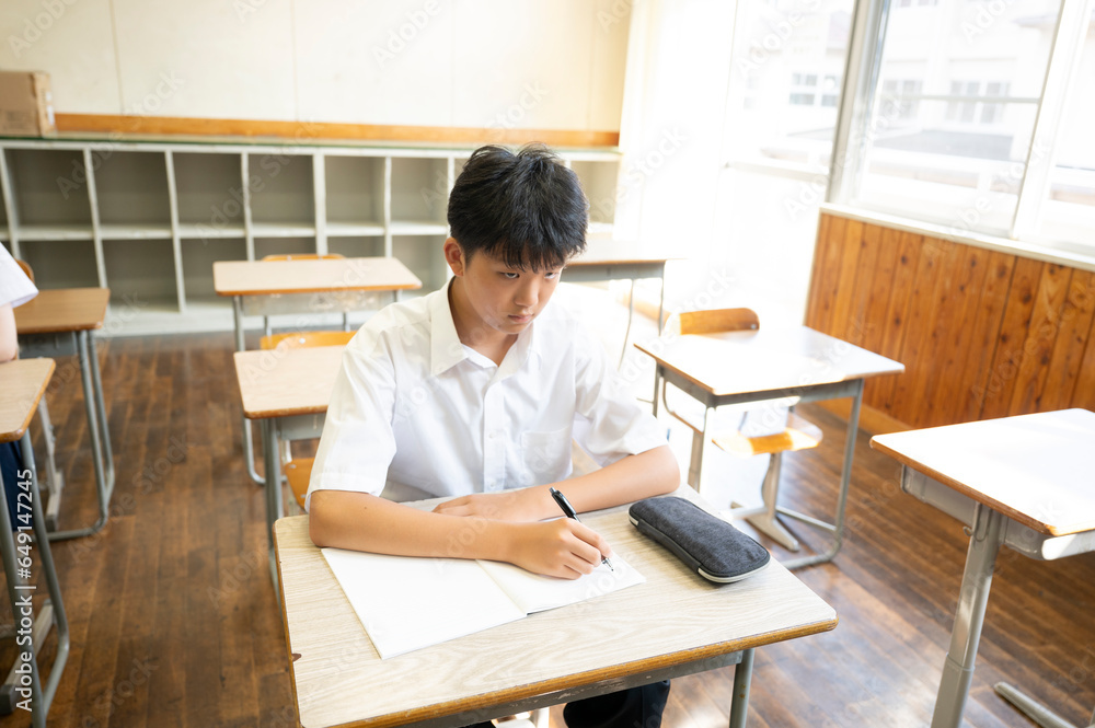学校の教室で授業を受ける男子生徒 学校の教室で授業を受ける男子生徒