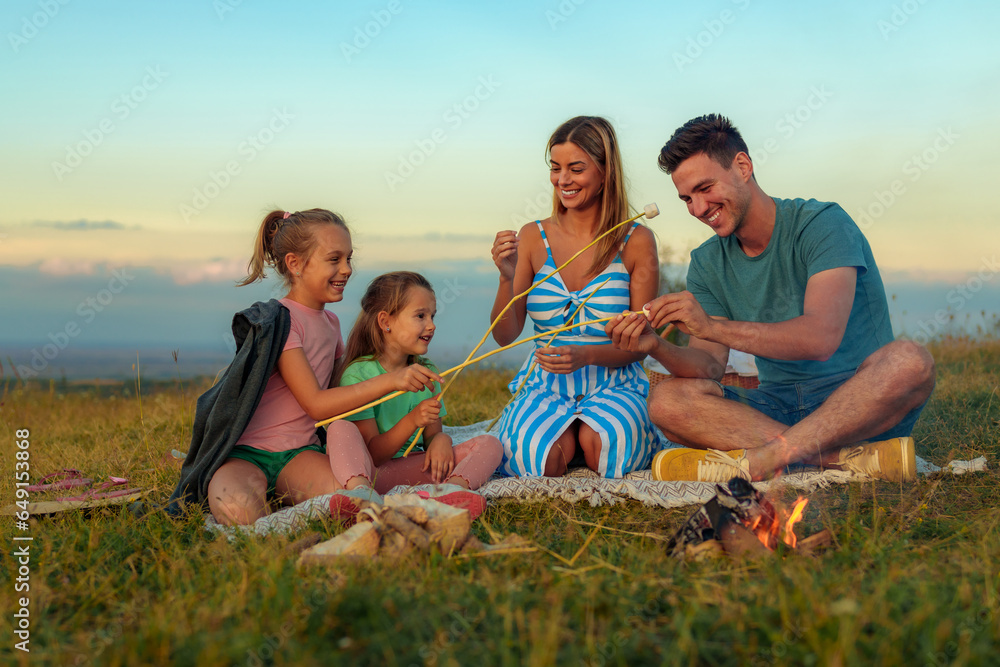 A happy family makes marshmallows by the fire, blended family bounding together. Stepfather teaching his stepdaughter to make marshmallows