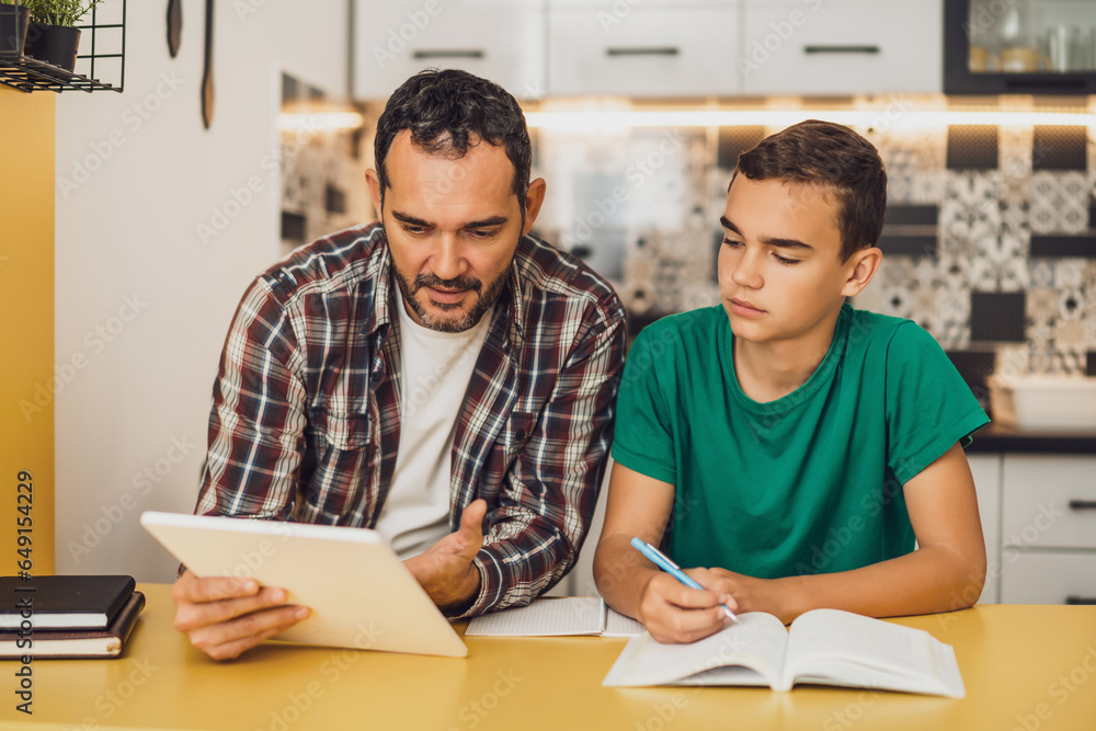 Father is helping his son with learning. They are doing homework together. Father is helping his son with learning. They are doing homework together.