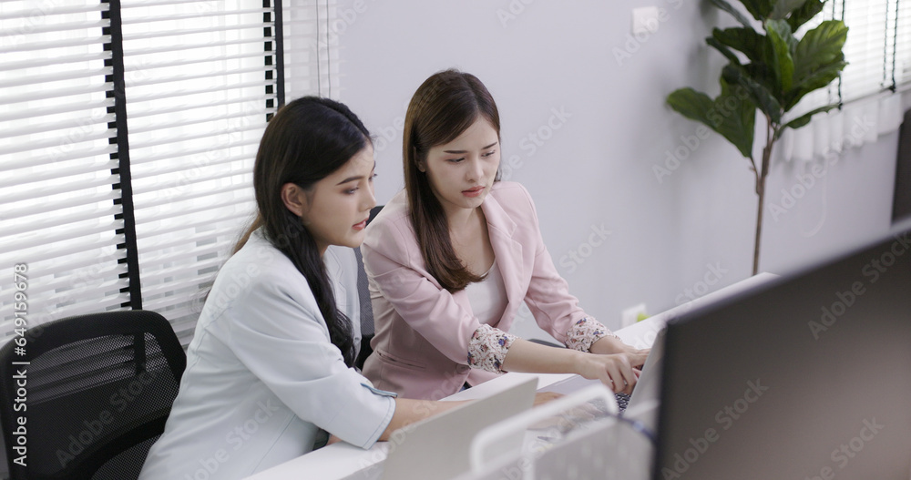 Two Asian business women are sitting and working in the office. Teamwork will make the team successful. Working with data technology is good business planning. Two Asian business women are sitting and working in the office. Teamwork will make the team successful. Working with data technology is good business planning.