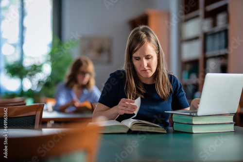 A visually impaired young woman sitting and studying in the university library © sepy