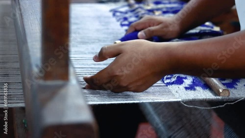 closeup of hands weaving warp loom through weaving frame, white and deep indigo blue cotton fabric yarns photo