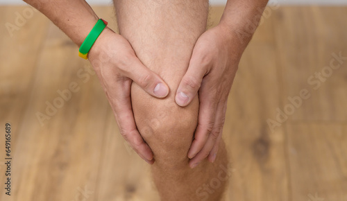 Ból kolana z bliska, dłonie położone na kolanie 