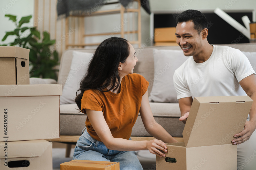 young couple helps put things in boxes and prepares, smiling happy moving to a new house. young couple helps put things in boxes and prepares, smiling happy moving to a new house.