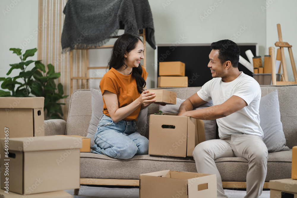 young couple helps put things in boxes and prepares, smiling happy moving to a new house. young couple helps put things in boxes and prepares, smiling happy moving to a new house.
