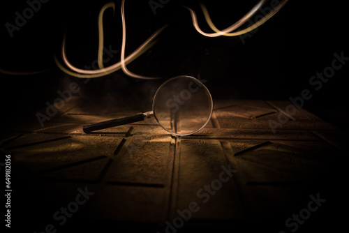Magnifying glass in dark blue background, under the light, mysterious detective concept