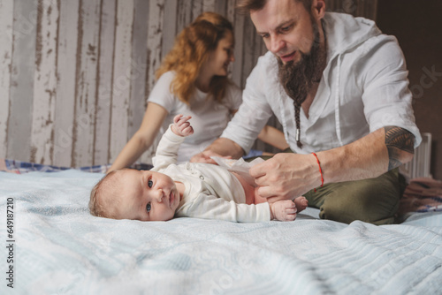 Father changing newborn daughter's diaper on bed at home photo