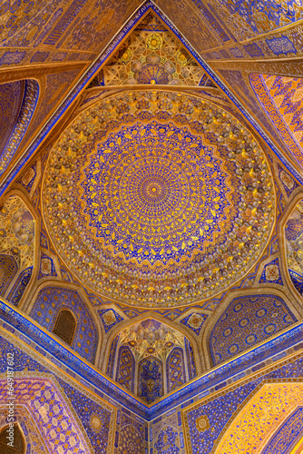 Painted gilded dome of Madrasa Tilya Kori  Registan complex . Arabic text of Koran  sacred book of muslims  used as part of ornament. Gold and blue  vertical. Samarkand  Uzbekistan