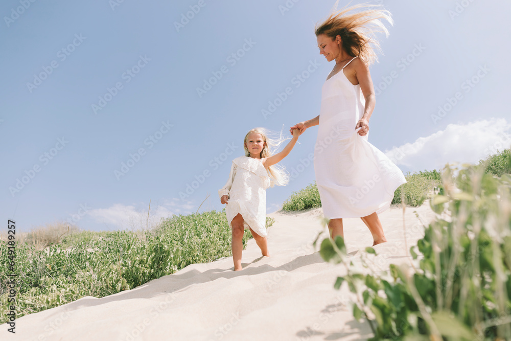 Mother and daughter holding hands and walking at beach Mother and daughter holding hands and walking at beach