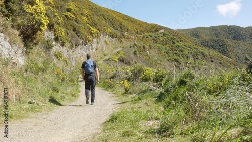 A day hiker walking up a steep gravel trail. Tip Track, Wellington, New Zealand