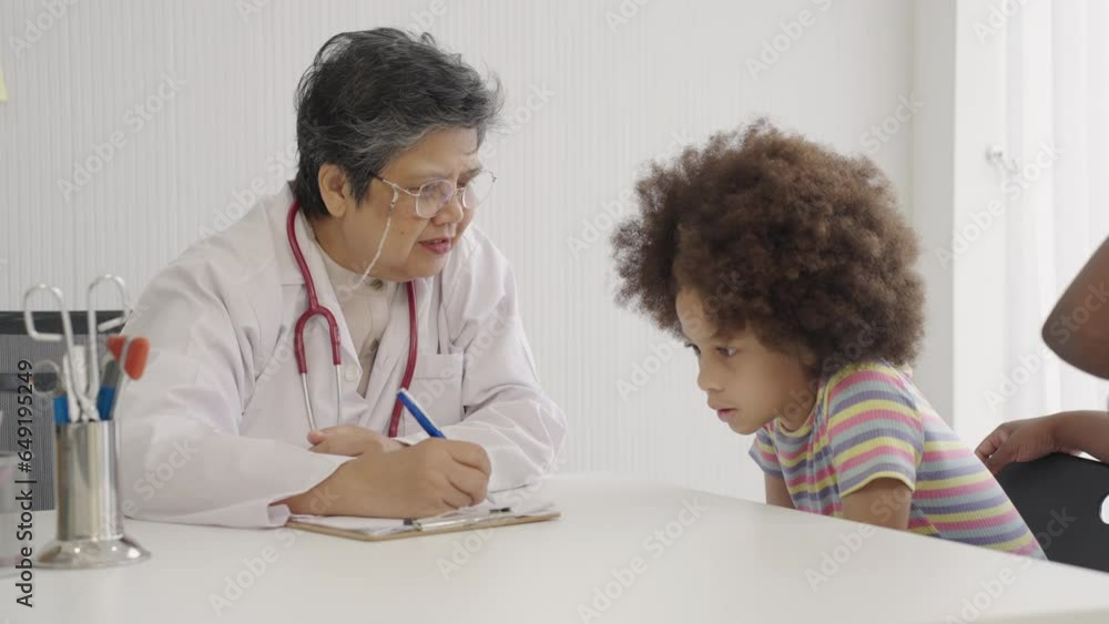Senior Asian female doctor treating black child patient. Senior Asian female doctor treating black child patient.