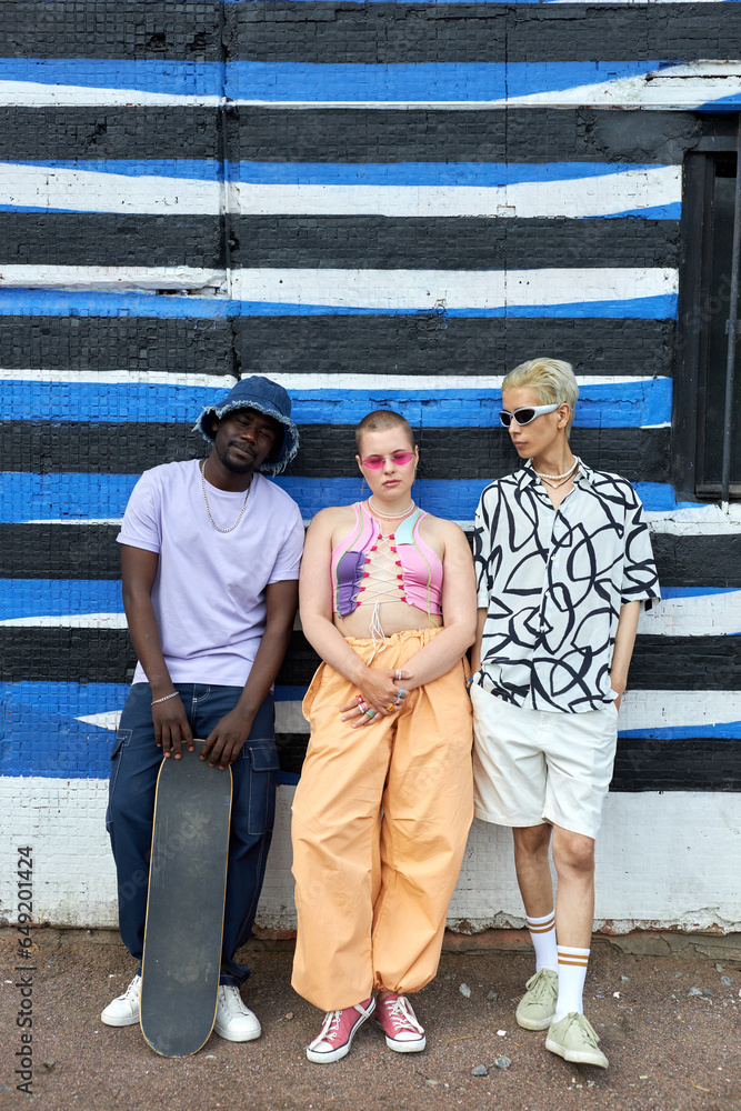 Full length portrait of multiethnic group of young people wearing trendy outfits posing as a band in urban setting