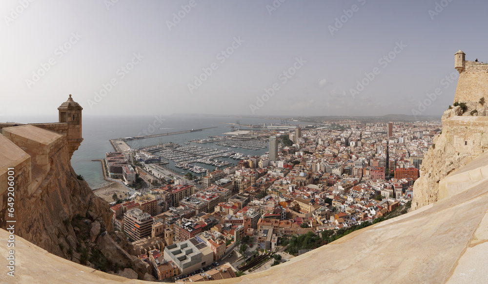 Panorámica de Alicante entre las gritas del castillo de santa bárbara ,  vista aérea de la ciudad. - obrazy, fototapety, plakaty 