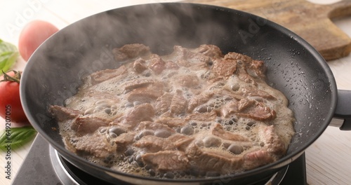 Sliced pieces of meat are fried in a frying pan. Roasting beef in a pan. Cooking in the kitchen. Food preparation.