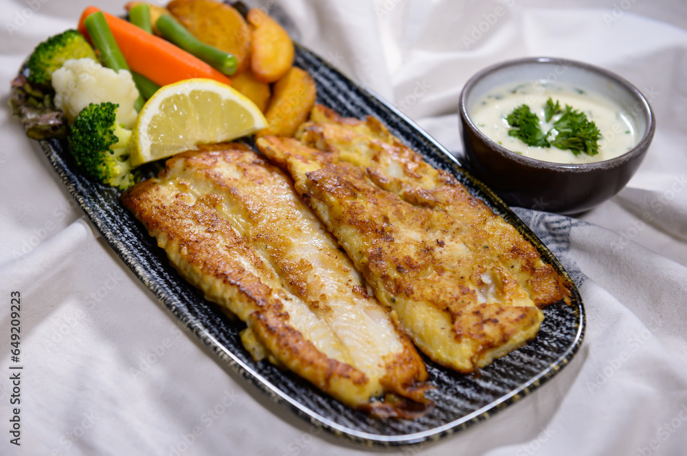 Grilled Hamour fish with fried veggies, lemon and salad served in dish isolated on food table top view of middle east spices Grilled Hamour fish with fried veggies, lemon and salad served in dish isolated on food table top view of middle east spices