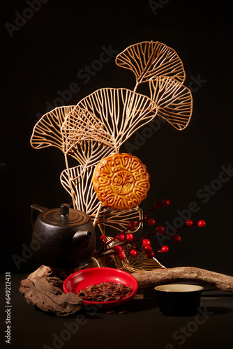 Mid-Autumn Festival themed art decoration with moon cakes, tea set in black color and a plate of melon seeds. Mid-autumn festival mooncake minimalist style tea party table