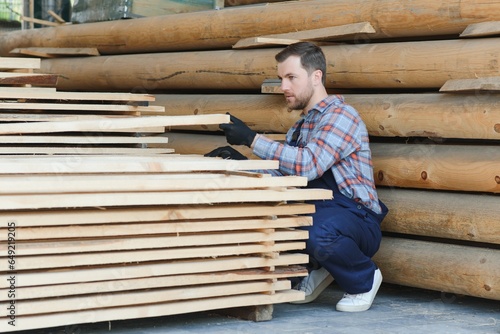 Builder holds wooden planks. Concept - sale of lumber. Builder is considering wood planks. Concept - wood processing business. wood timber stack of wooden planks.